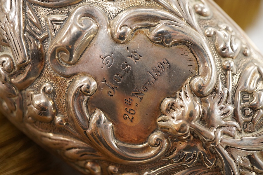 A late Victorian embossed silver four piece dressing table mirror and brush set, by William Comyns, London, 1891/5 and a similar clothes brush.